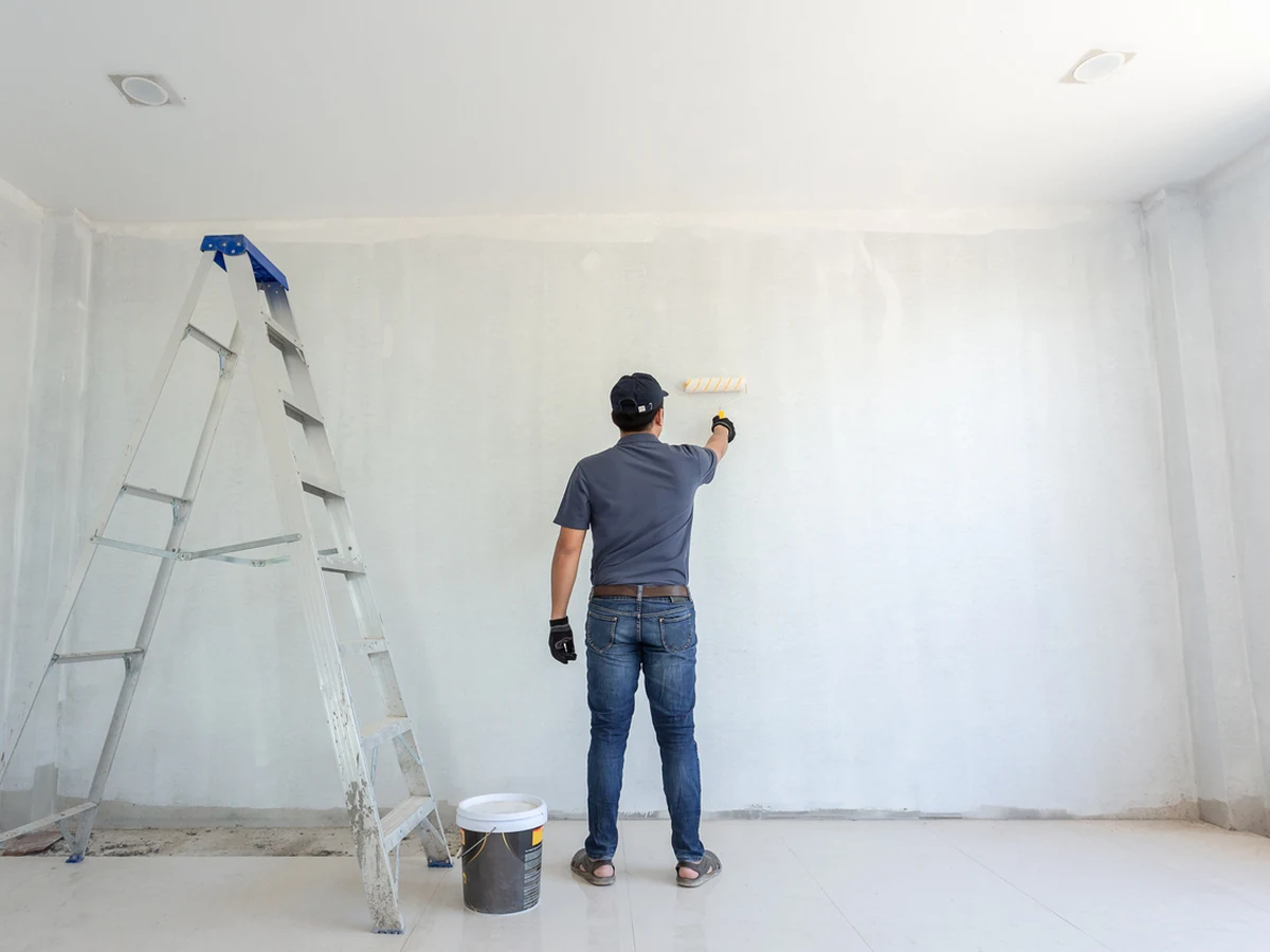 Decorator painting grey and white walls in Haywards Heath