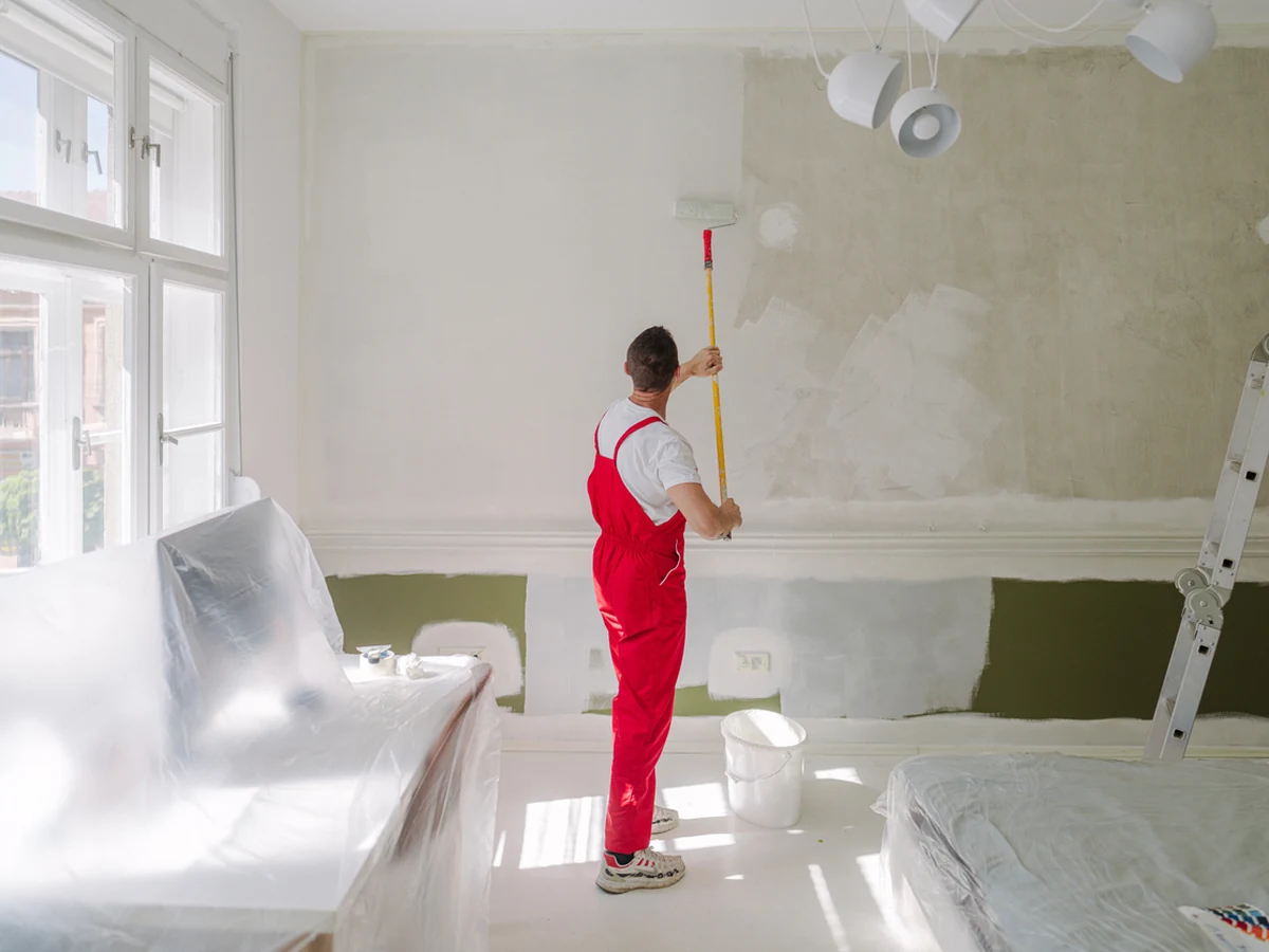 Decorator in red overalls painting walls in Haywards Heath
